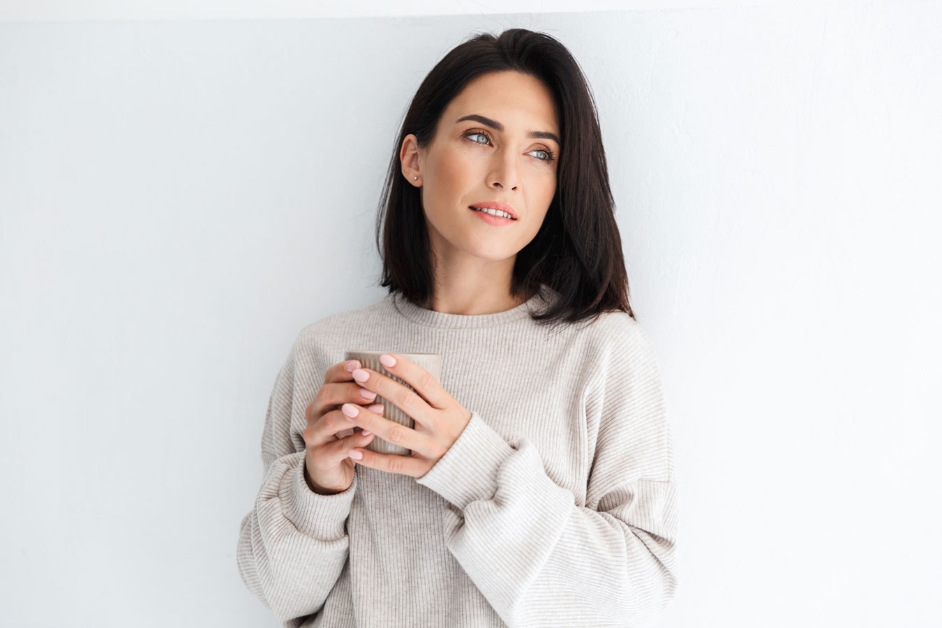 Frau hält Tasse, strahlt Ruhe und Selbstvertrauen aus.