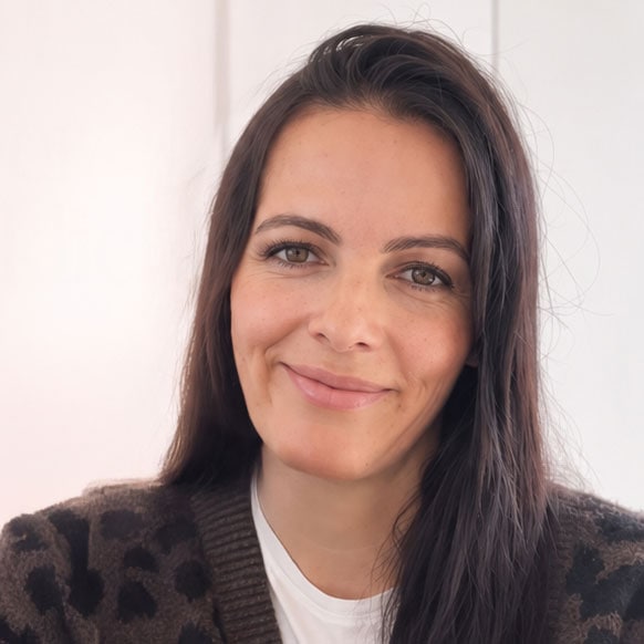 Lächelnde Frau mit dunklem Haar und freundlichem Blick.